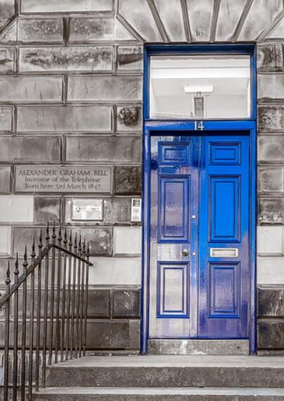 A blue door with a plaque besides it reading